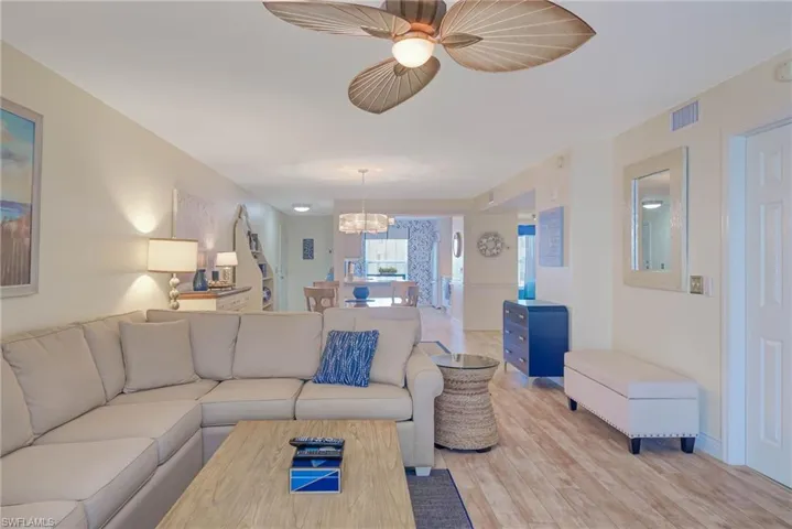 Living room with ceiling fan with notable chandelier and light hardwood / wood-style flooring