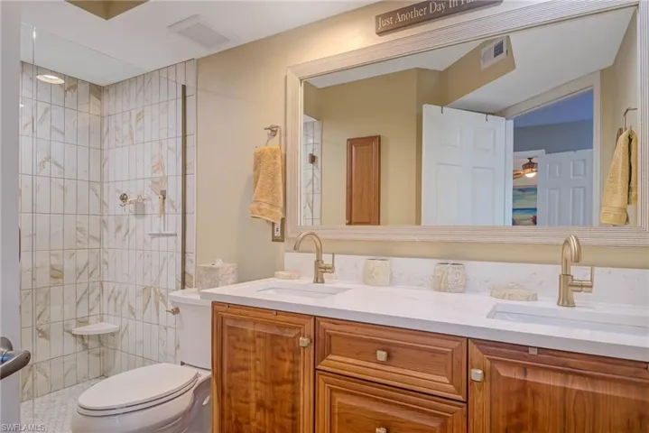 Bathroom with vanity, ceiling fan, toilet, and tiled shower