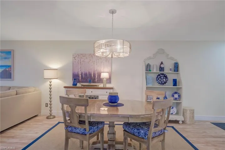 Dining area with built in features, light hardwood / wood-style floors, and an inviting chandelier
