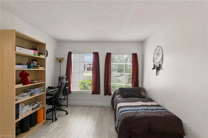 Bedroom with an office area, light wood-type flooring, and a textured ceiling