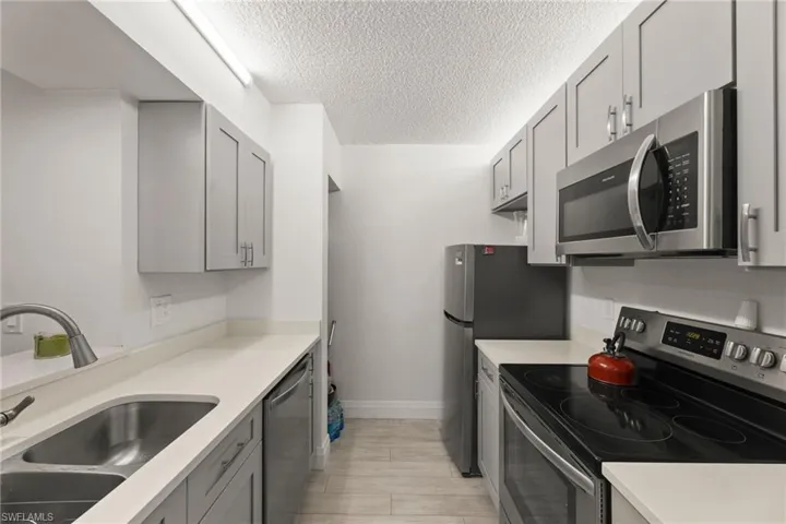 Kitchen featuring stainless steel appliances, gray cabinets, and a textured ceiling
