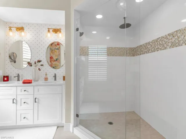 Bathroom with a tile shower, tile patterned flooring, and vanity