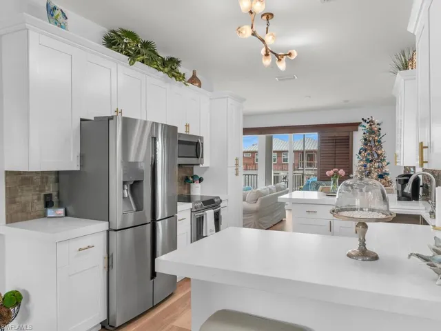 Kitchen featuring kitchen peninsula, white cabinetry, stainless steel appliances, and tasteful backsplash