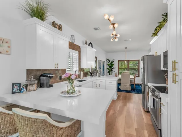 Kitchen featuring kitchen peninsula, white cabinets, and appliances with stainless steel finishes