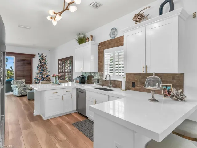 Kitchen with white cabinets, dishwasher, light hardwood / wood-style floors, and kitchen peninsula