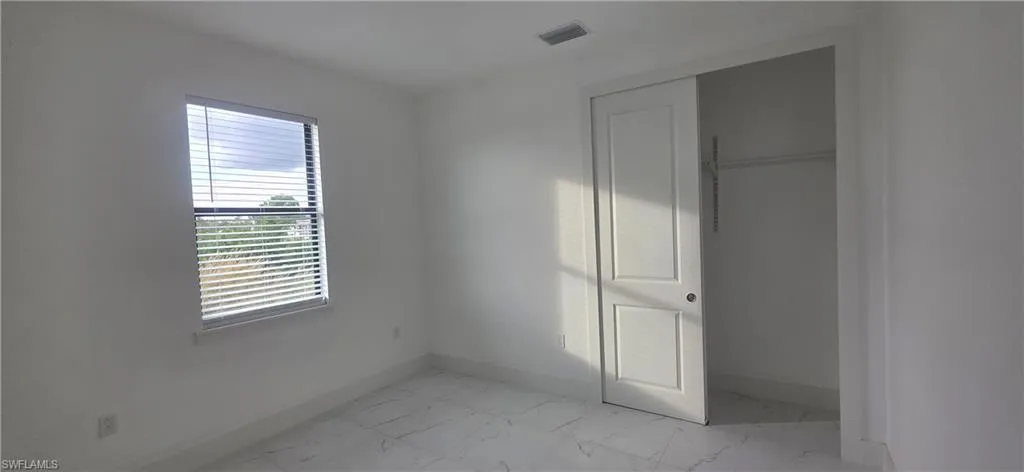 Unfurnished bedroom with a closet and light marble finish flooring