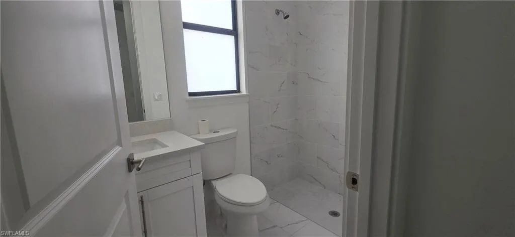 Full bathroom with a shower stall, vanity, and marble look tile flooring