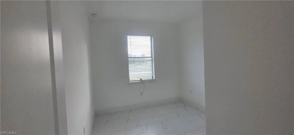 Spare room featuring light marble finish floors and baseboards