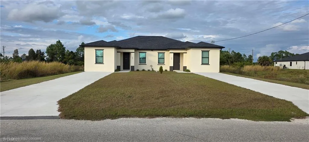 View of front of property with stucco siding, concrete driveway, and a front lawn