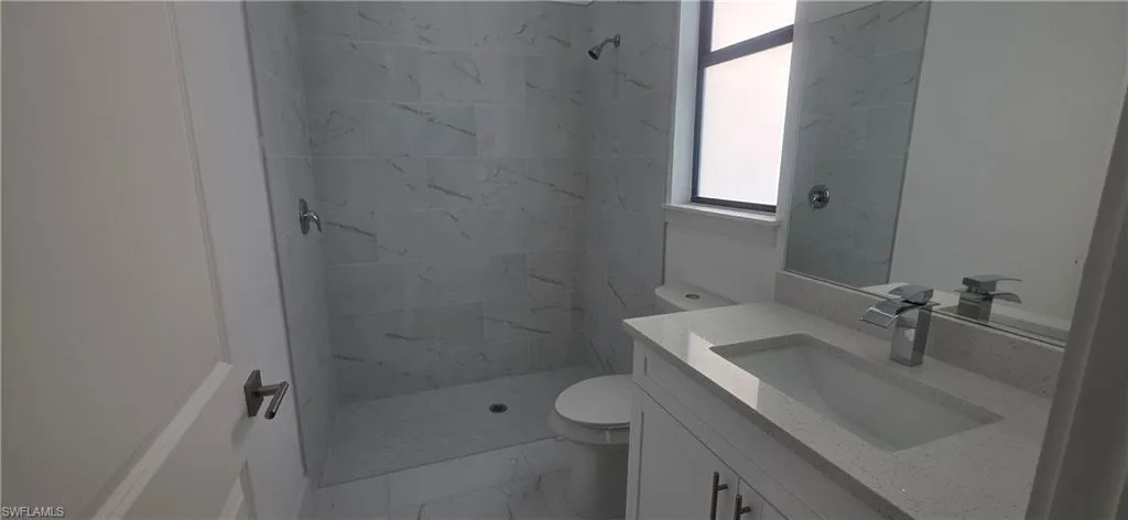 Bathroom with a marble finish shower, vanity, and light marble finish floors
