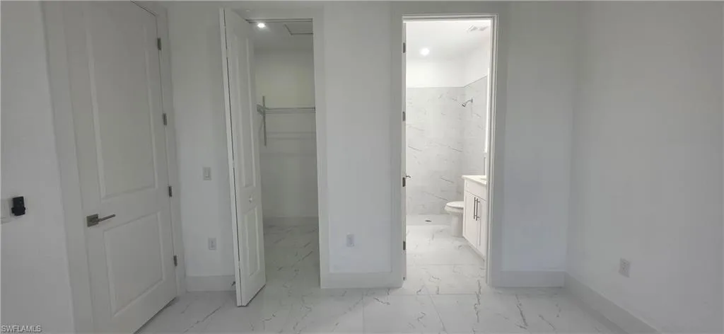 Full bathroom with light marble finish floors, a spacious closet, vanity, and a marble finish shower