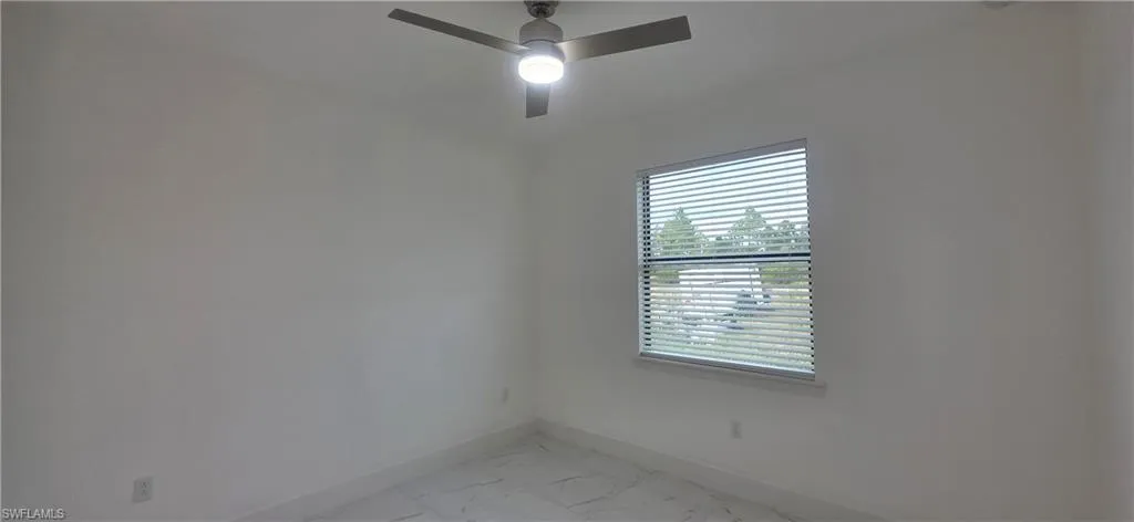 Unfurnished room with light marble finish flooring and a ceiling fan