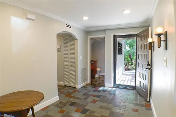 Foyer entrance with ornamental molding, stone tile flooring, arched walkways, and recessed lighting