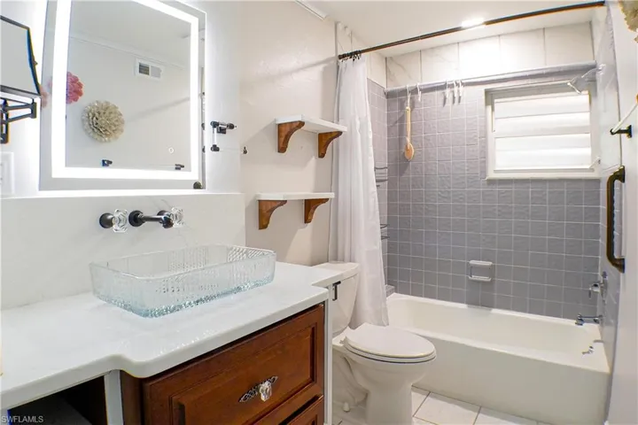Full bath with shower / bath combination with curtain, vanity, and light tile patterned floors