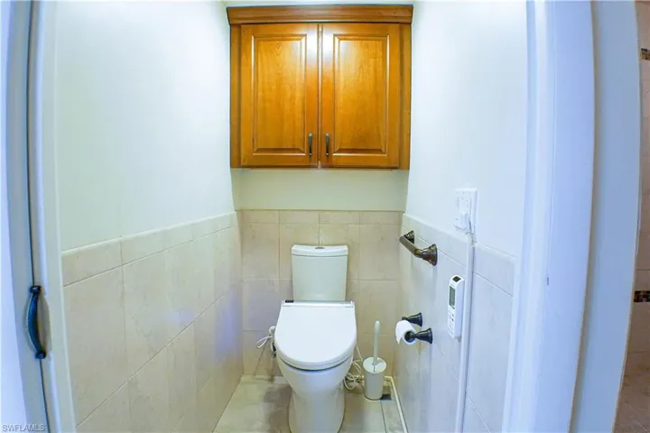 Bathroom with tile patterned floors, a wainscoted wall, and tile walls