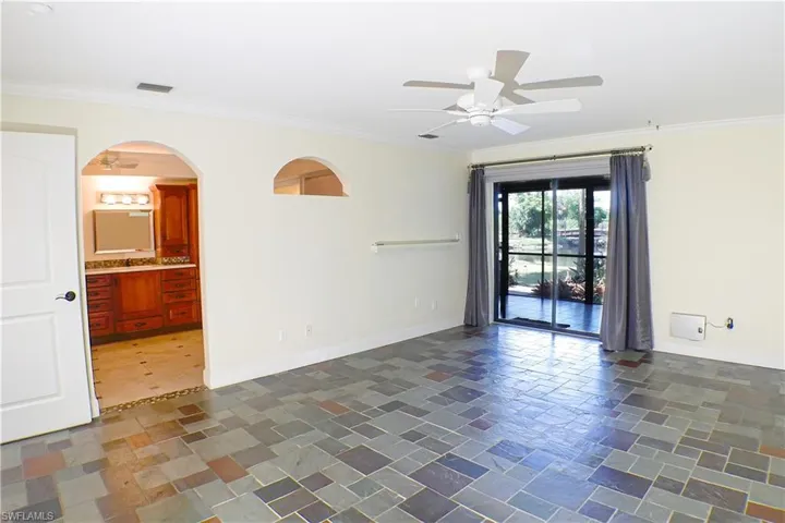 Unfurnished room with ceiling fan, ornamental molding, and arched walkways