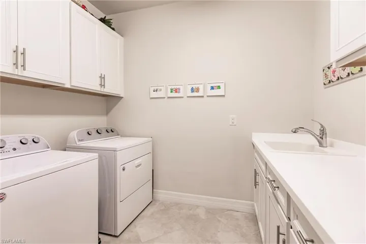 Full size laundry room with upgraded cabinets, counters and laundry sink.