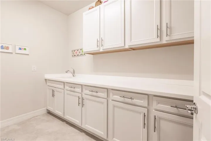 Full size laundry room with upgraded cabinets, counters and laundry sink.