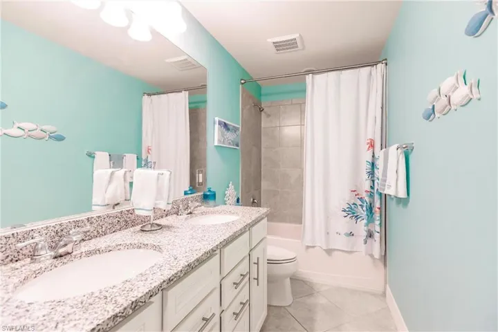 Full bathroom #2 with tile patterned floors, vanity, toilet, and shower/tub combination