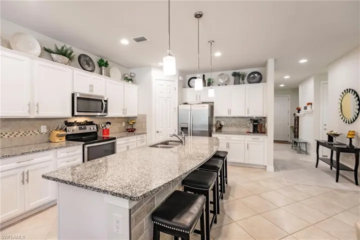 Kitchen featuring white cabinets, backsplash, a large kitchen island and stainless-steel appliances.