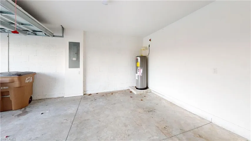 Utility room featuring a water heater, concrete flooring, painted block walls, and an electrical panel