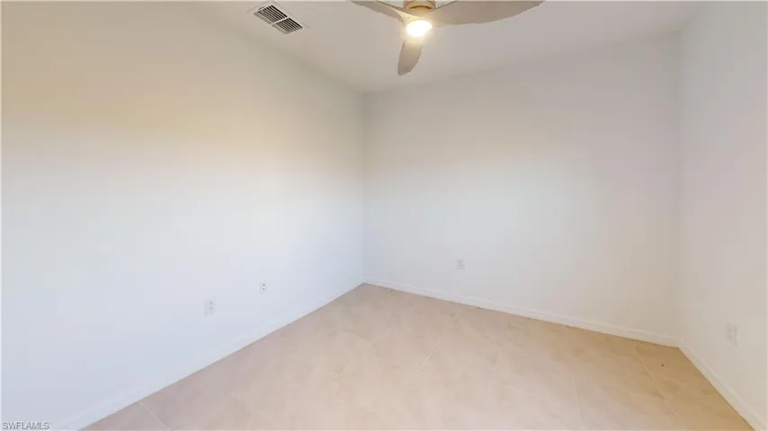 Interior room featuring neutral-toned tile flooring and white baseboards