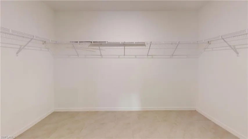 Walk-in closet featuring light-toned tile flooring, white baseboards, and comprehensive wire shelving system