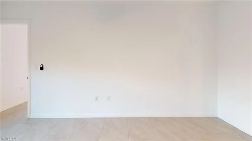 Light-toned tile flooring, white baseboards, and a doorway with white trim