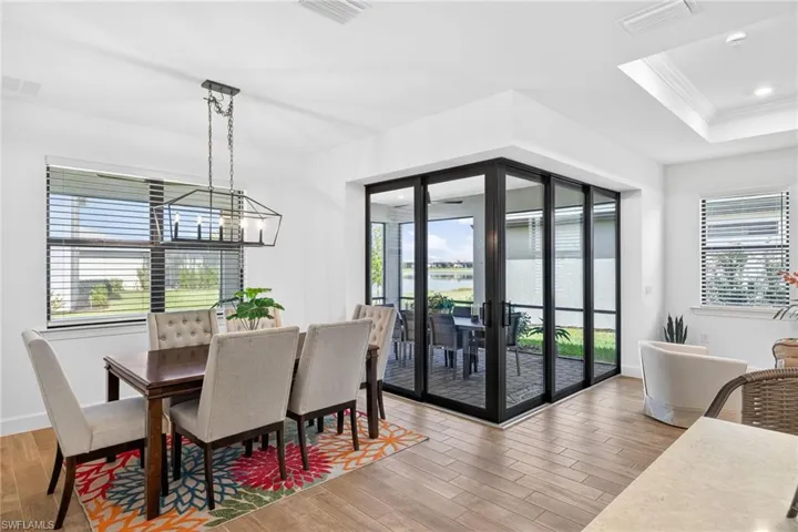 Dining area with light wood-type flooring, ornamental molding, a raised ceiling, and a water view