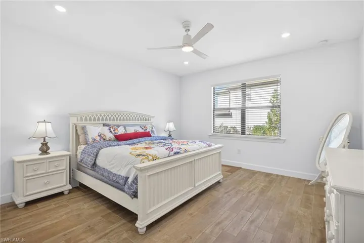 Bedroom with light wood-style floors, ceiling fan, and recessed lighting