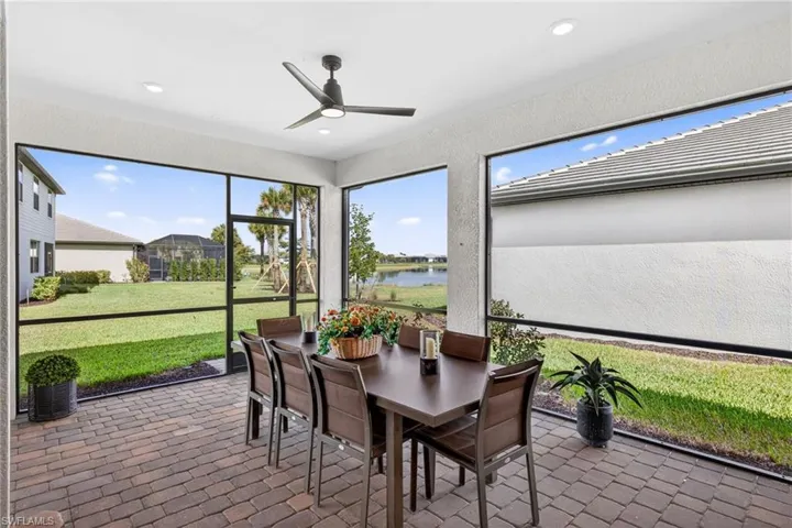 Sunroom / solarium with outdoor dining area, ceiling fan, a water view, and a patio