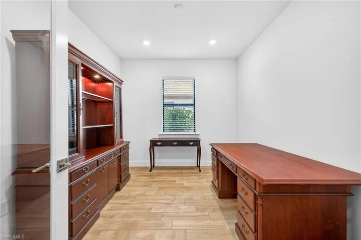 Office area with light wood-style floors and recessed lighting