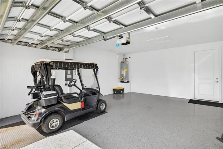 Garage featuring water heater, a garage door opener, and concrete block wall