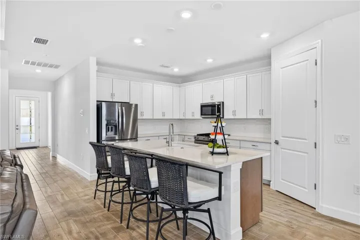 Kitchen featuring white cabinetry, a kitchen breakfast bar, a kitchen island with sink, light wood-type flooring, and stainless steel appliances