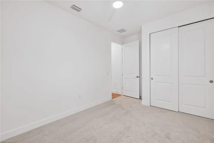 Unfurnished bedroom featuring light colored carpet, a ceiling fan, and a closet