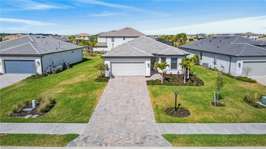 Ranch-style home featuring a garage, a front yard, a residential view, and decorative driveway