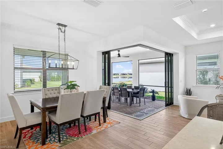Dining room with ornamental molding, light wood finished floors, a raised ceiling, a water view, and a ceiling fan