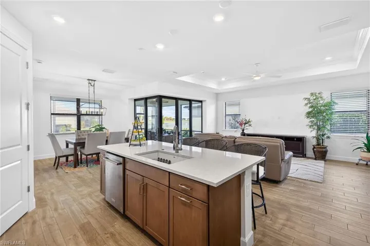 Kitchen featuring wood finish cabinets, a kitchen bar, light wood finished floors, a center island with sink, and open floor plan