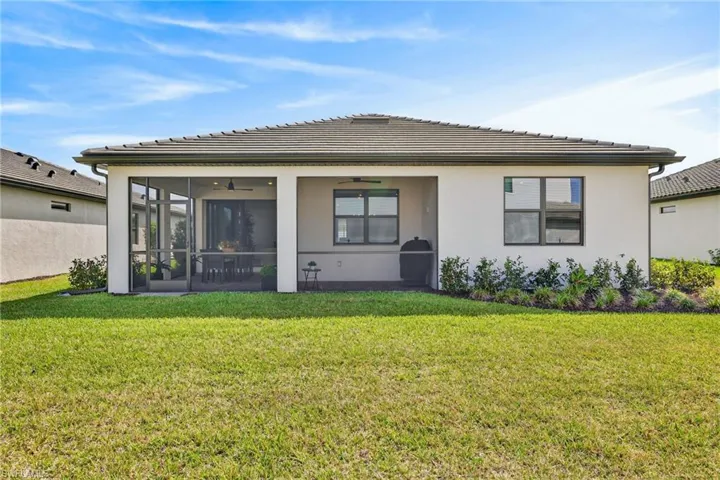 Back of house featuring a yard, stucco siding, a tiled roof, ceiling fan, and a sunroom