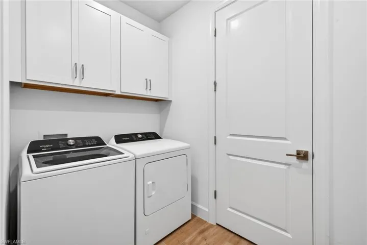 Laundry room with light wood-type flooring, cabinet space, and washing machine and dryer