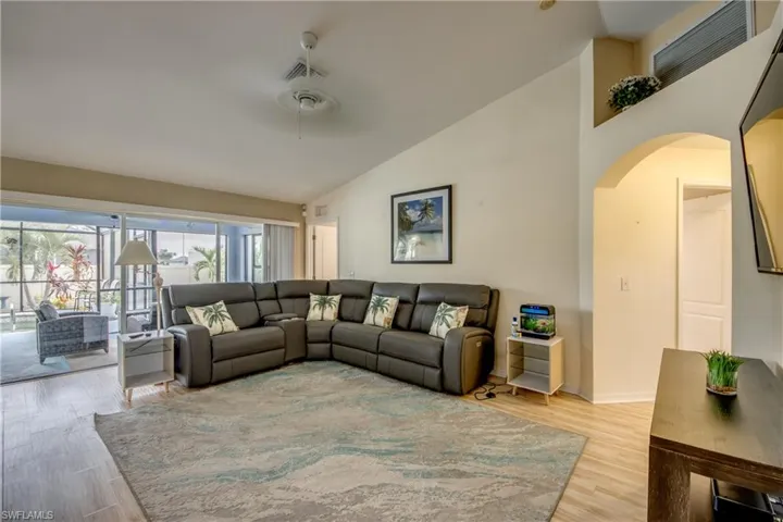 Living room featuring ceiling fan, high vaulted ceiling, and light wood-type flooring