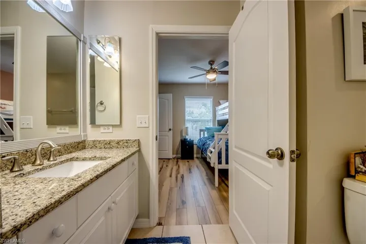 Bathroom featuring vanity, hardwood / wood-style flooring, toilet, and ceiling fan