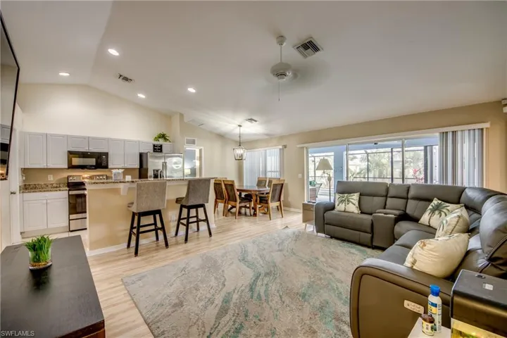 Living room with ceiling fan, vaulted ceiling, and light wood-type flooring