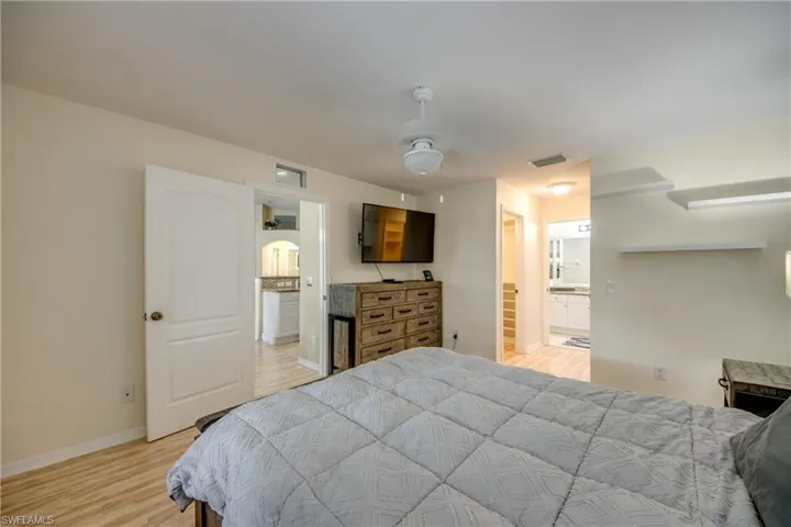 Bedroom with ensuite bathroom, light hardwood / wood-style flooring, and ceiling fan