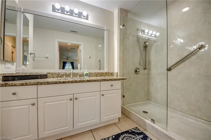 Bathroom with a tile shower, tile patterned flooring, and vanity