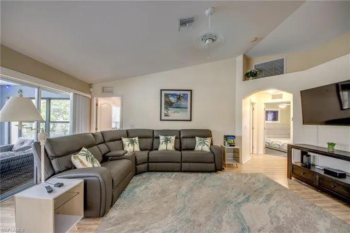 Living room featuring light hardwood / wood-style floors, ceiling fan, and lofted ceiling
