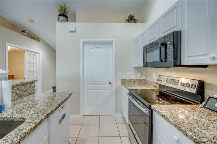 Kitchen featuring light stone countertops, white cabinets, dishwasher, stainless steel electric range oven, and light tile patterned flooring