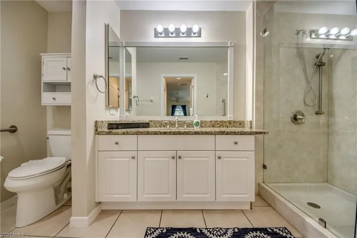 Bathroom featuring tile patterned flooring, vanity, toilet, and a tile shower