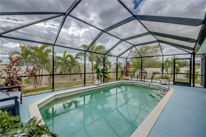 View of swimming pool with glass enclosure and a patio area