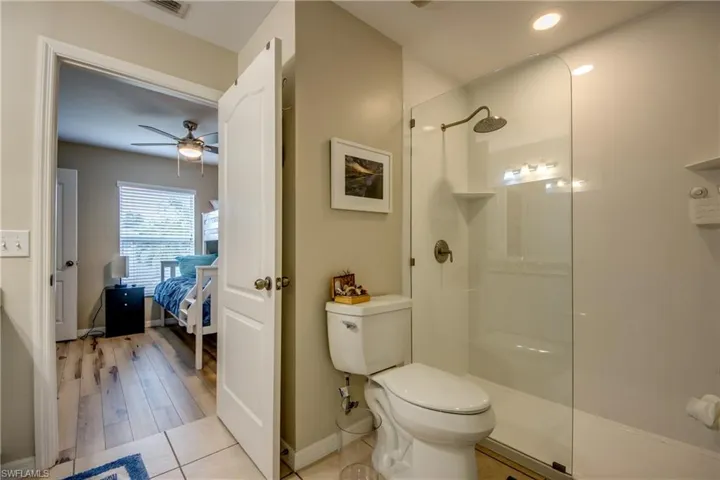 Bathroom with ceiling fan, hardwood / wood-style floors, a shower, and toilet
